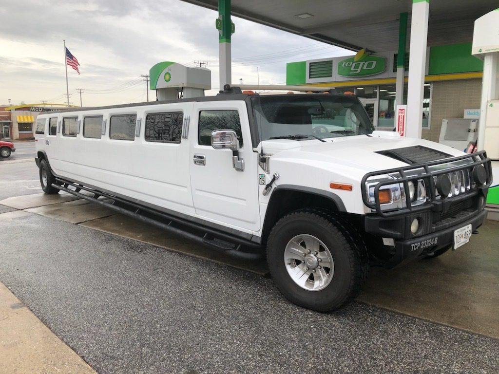 A white limo parked in front of a gas station.