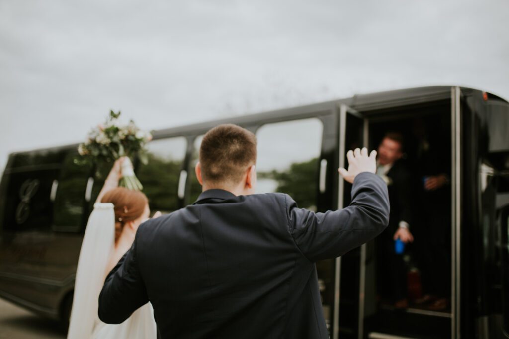 A man waving to people on the side of a bus.